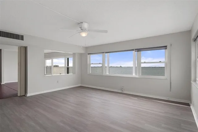 an empty room with wooden floor and windows