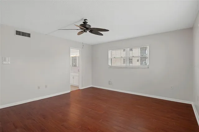 a view of an empty room with a window and wooden floor