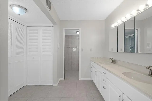 a spacious bathroom with a double vanity sink a large mirror and a shower