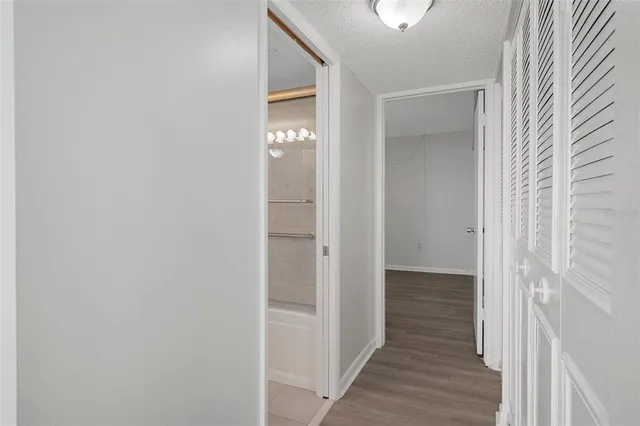 a view of a hallway with wooden floor and a bathroom