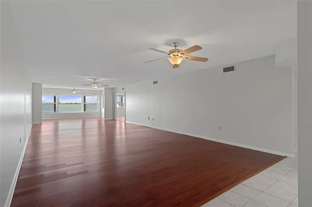 an empty room with wooden floor and chandelier fan