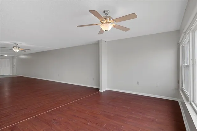 an empty room with wooden floor fan and window