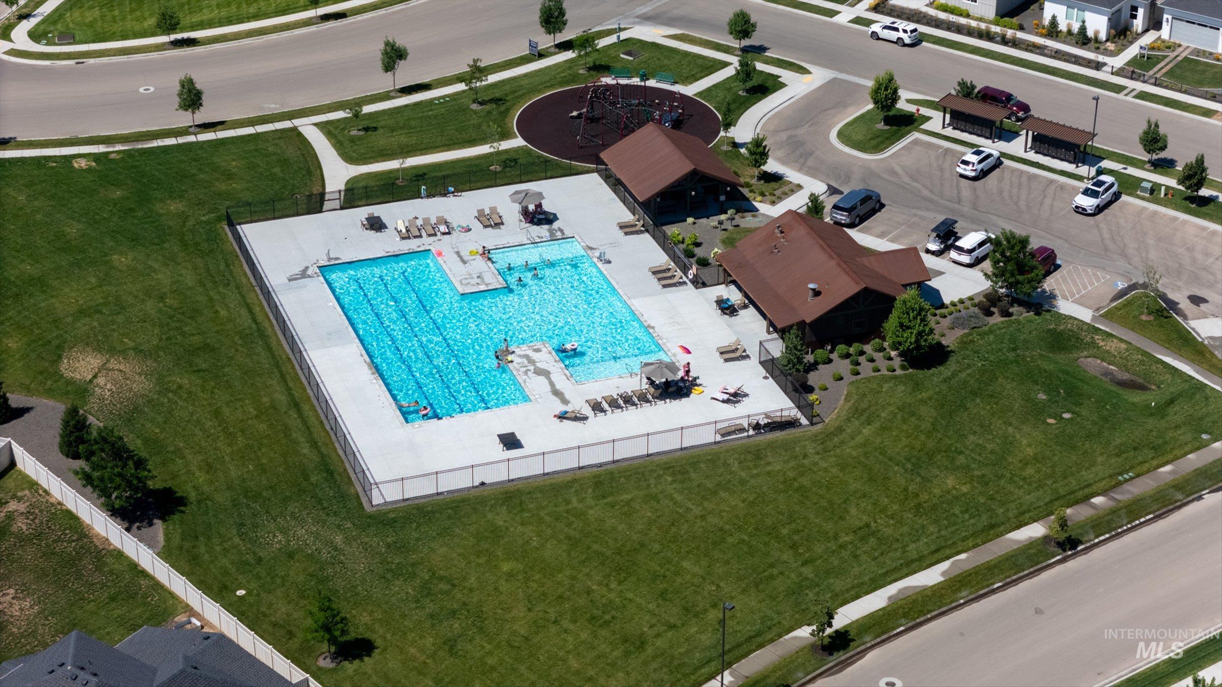 2172 Savoy Court Middleton, ID 83644 - Photo 43 of 46 Community pool area featuring a large swimming pool, surrounding paved patio, fenced perimeter, and a clubhouse building with a brown roof