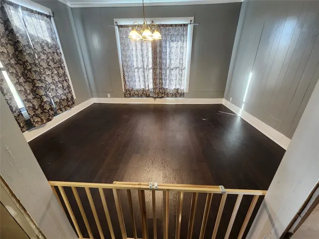 en empty room with wooden floor and fan