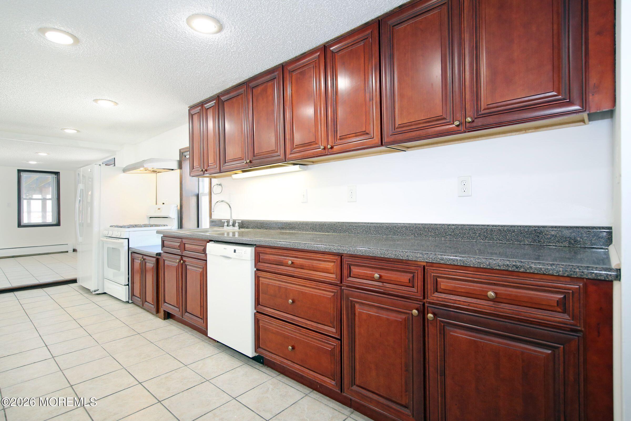 60 Matthew Street, Unit 1 Highlands, NJ 07732 - Photo 10 of 33 a kitchen with stainless steel appliances granite countertop a refrigerator and wooden cabinets