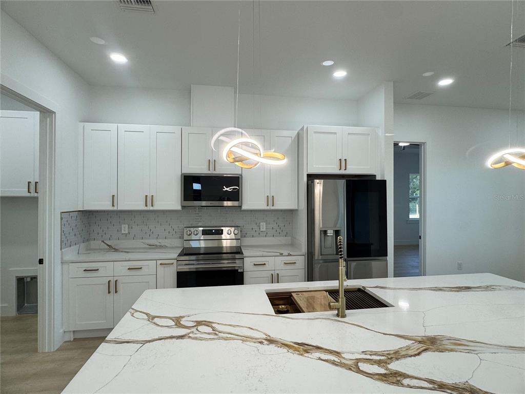 1721 McClellan Road Frostproof, FL 33843 - Photo 7 of 41 a kitchen with granite countertop a sink stainless steel appliances and cabinets