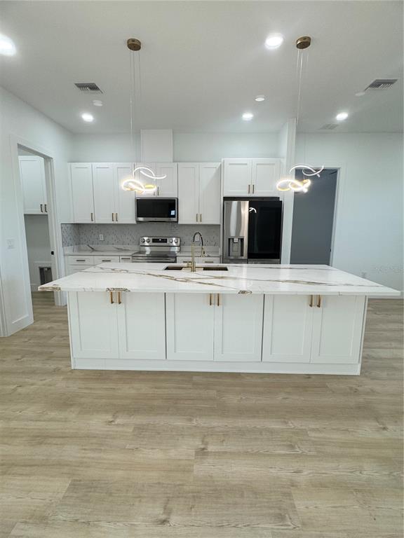 1721 McClellan Road Frostproof, FL 33843 - Photo 8 of 41 a view of kitchen with stainless steel appliances granite countertop a stove a sink a refrigerator and white cabinets with wooden floor