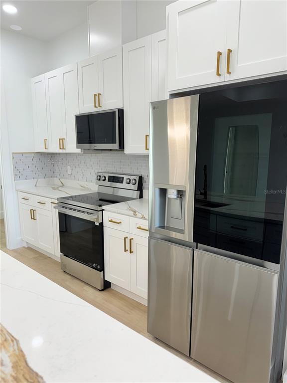 1721 McClellan Road Frostproof, FL 33843 - Photo 9 of 41 a kitchen with stainless steel appliances granite countertop a refrigerator a stove a sink and dishwasher with wooden floor