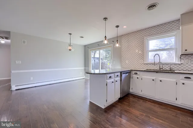 a kitchen with granite countertop wooden floors and white cabinets