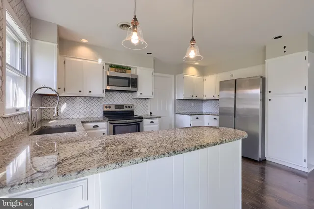 a kitchen with stainless steel appliances granite countertop a sink refrigerator and microwave
