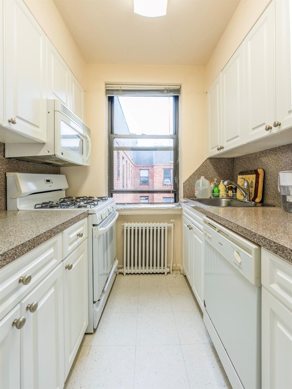 215-43 48th Avenue, Unit 3A Queens, NY 11364 - Photo 11 of 16 a kitchen with granite countertop white cabinets and white appliances