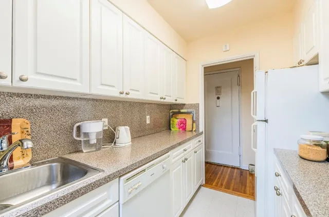 a kitchen with stainless steel appliances granite countertop a sink and a white cabinets with wooden floor
