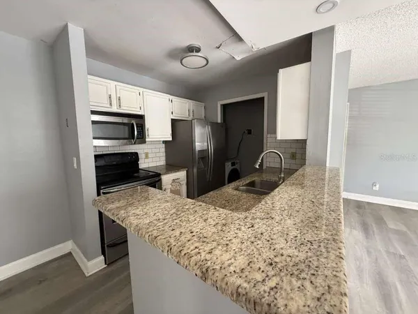 a kitchen with kitchen island granite countertop a stove microwave and refrigerator