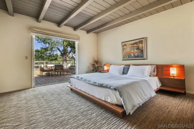 a spacious bedroom with a bed painting on wall and a large window