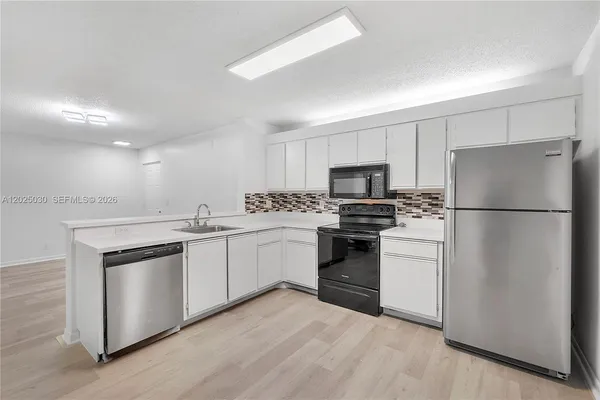 a kitchen with granite countertop white cabinets and stainless steel appliances