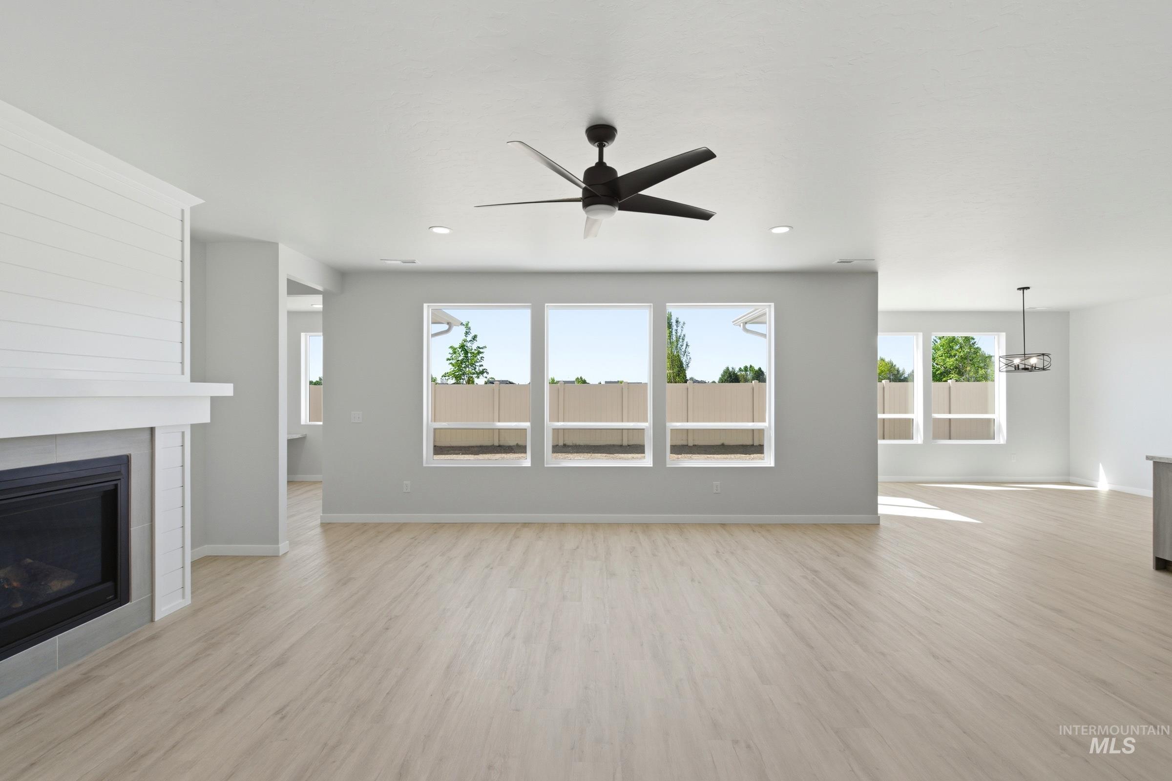13663 Redway Court Caldwell, ID 83607 - Photo 10 of 32 Spacious room featuring light wood-finish flooring, a fireplace with a white shiplap-style surround, large windows, recessed lighting, and a ceiling fan