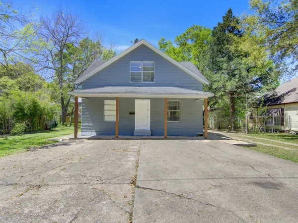 a front view of a house with a garden and tree