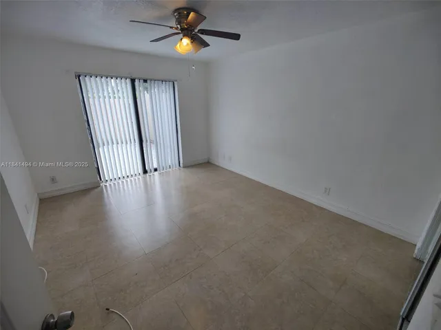 an empty room with a window and a chandelier fan