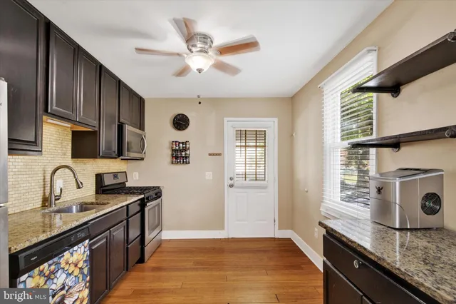 a kitchen with granite countertop stainless steel appliances a sink a stove cabinets and a window