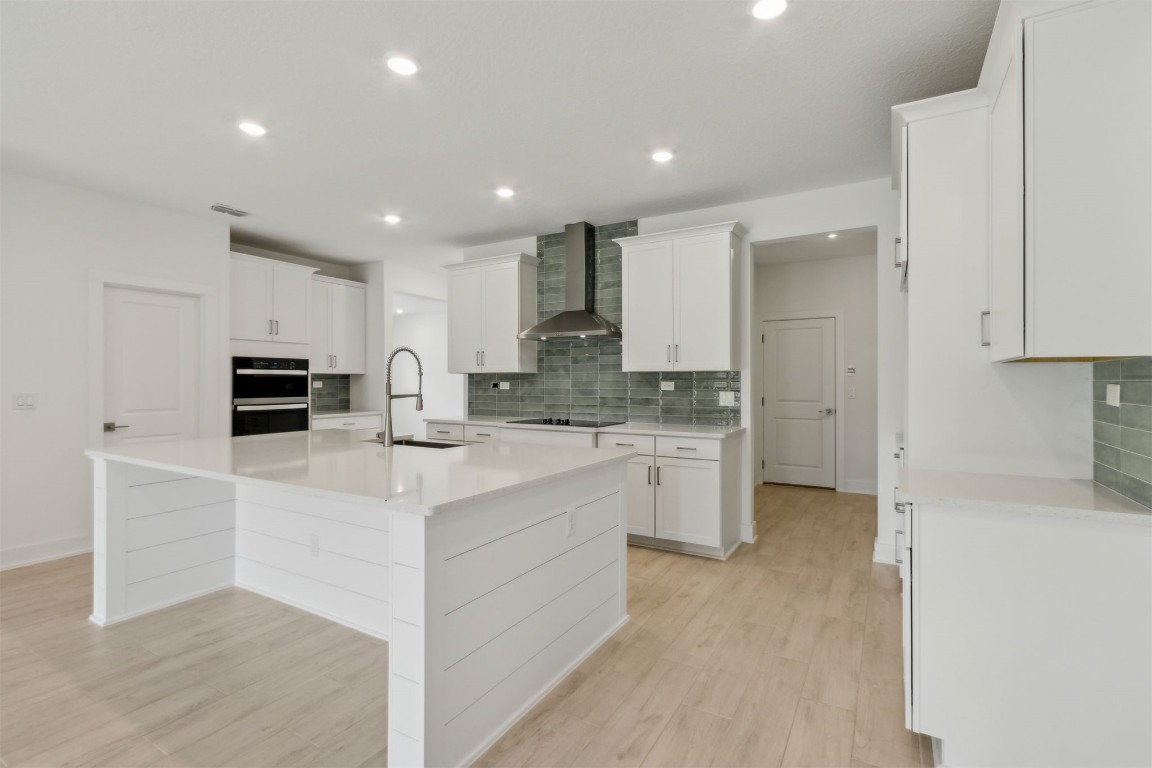 96088 Pirates Bluff Road Yulee, FL 32097 - Photo 11 of 25 a large white kitchen with kitchen island a sink a stove a refrigerator and white cabinets