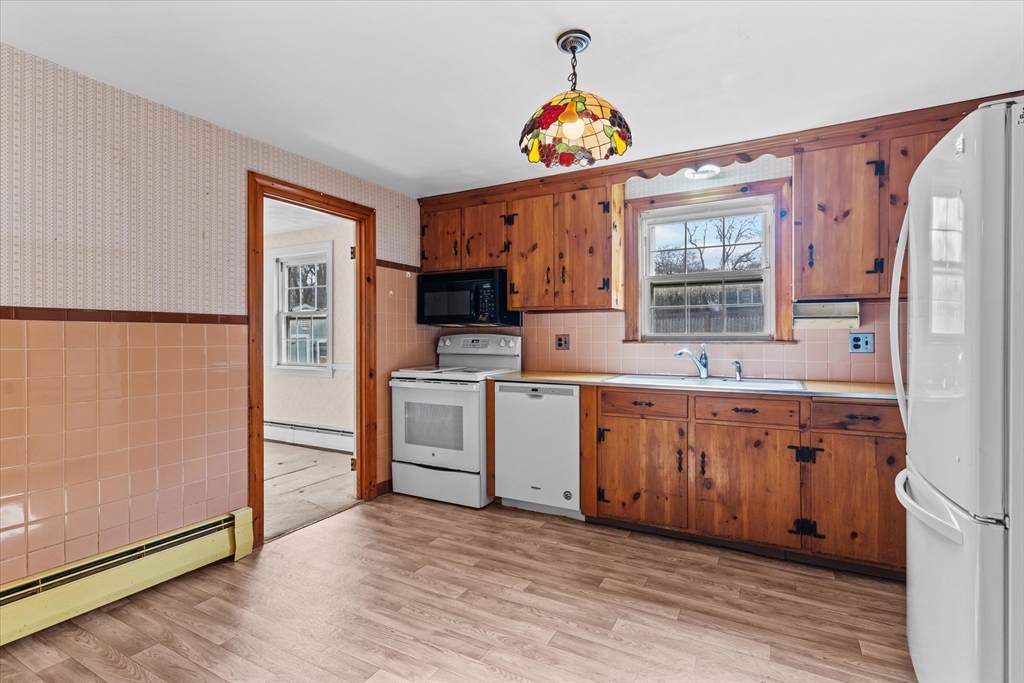 9 Pershing Road Salem, MA 01970 - Photo 13 of 42 a kitchen with granite countertop a refrigerator a sink dishwasher a stove and a dining table with wooden floor