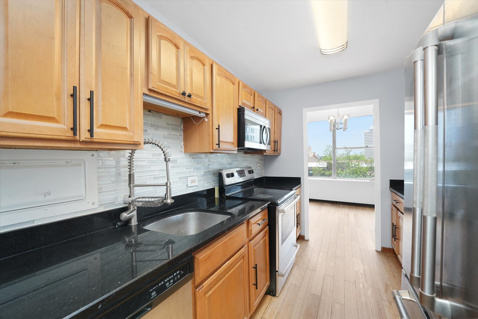 5757 North Sheridan Road, Unit 5J Chicago, IL 60660 - Photo 14 of 44 a kitchen with granite countertop a sink a stove and cabinets