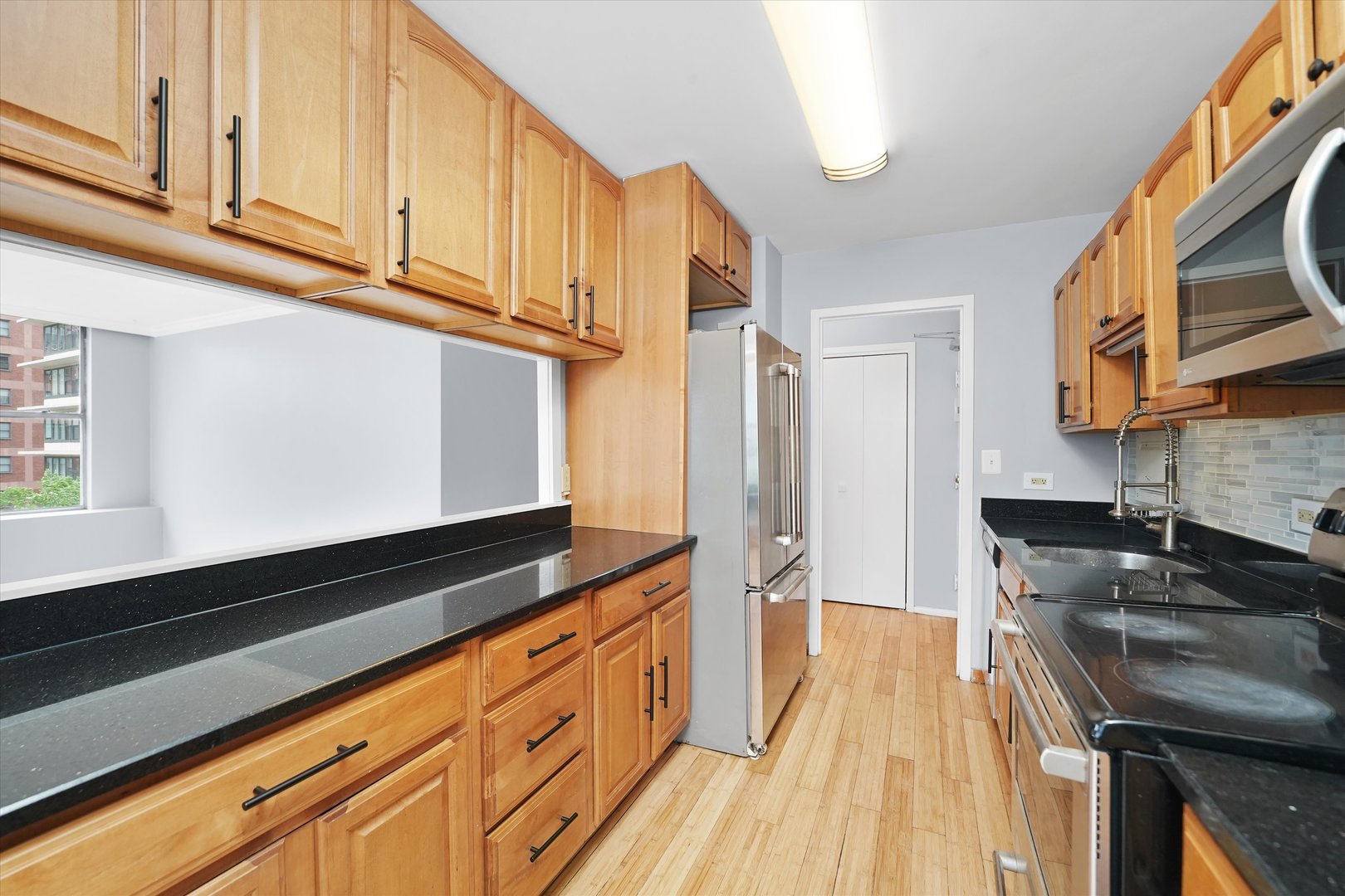 5757 North Sheridan Road, Unit 5J Chicago, IL 60660 - Photo 16 of 44 a kitchen with granite countertop wooden cabinets stainless steel appliances and a counter space