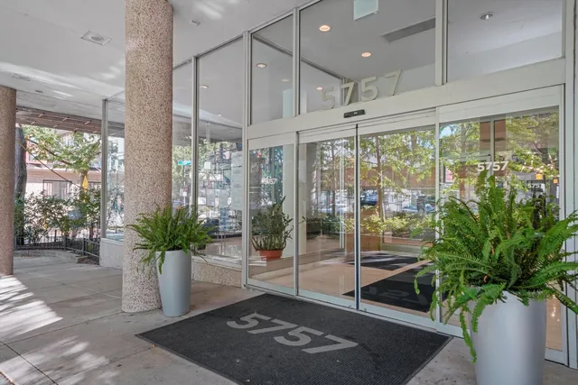 a living room with glass windows and flower plants