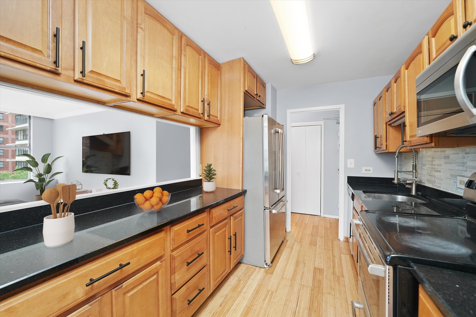 5757 North Sheridan Road, Unit 5J Chicago, IL 60660 - Photo 5 of 44 a kitchen with stainless steel appliances a sink a stove and a wooden floor