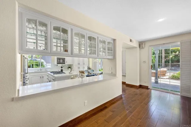 a kitchen with stainless steel appliances granite countertop a refrigerator a stove top oven a sink dishwasher and white cabinets with wooden floor