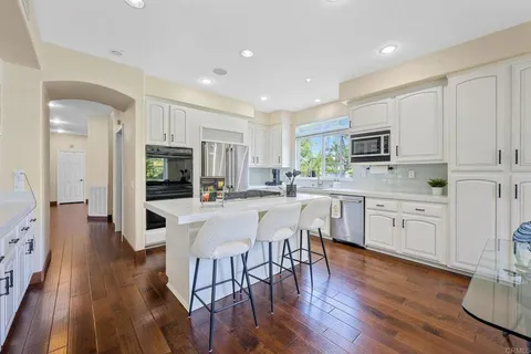 a kitchen with a stove a sink dishwasher a dining table and chairs with wooden floor