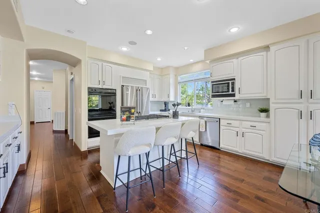 a kitchen with a stove a sink dishwasher a dining table and chairs with wooden floor