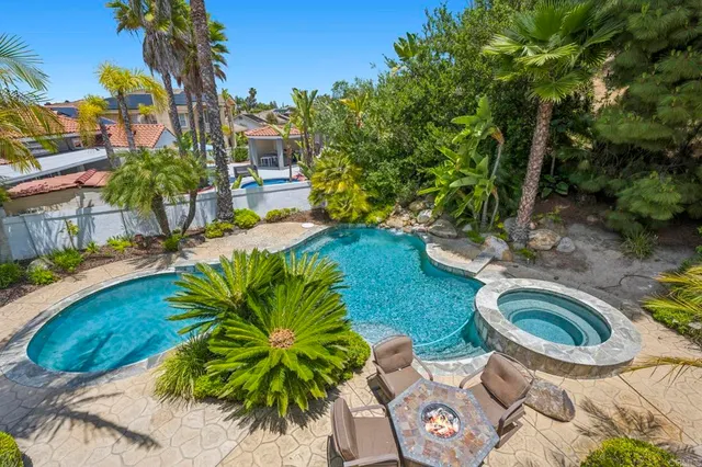 a backyard of a house with plants and palm tree