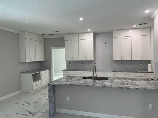 a kitchen with granite countertop a sink a stove and cabinets