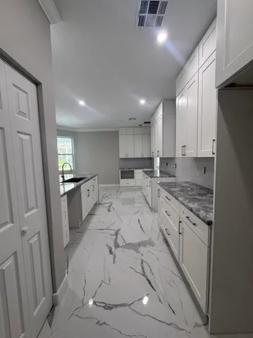 a large kitchen with a sink stainless steel appliances and cabinets