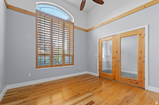 1501 West Elk Circle Mapleton, UT 84664 - Photo 13 of 39 Vaulted ceiling room featuring tall arched windows with plantation shutters, wood-finish flooring, natural wood trim accents, and French doors with clear glass panels