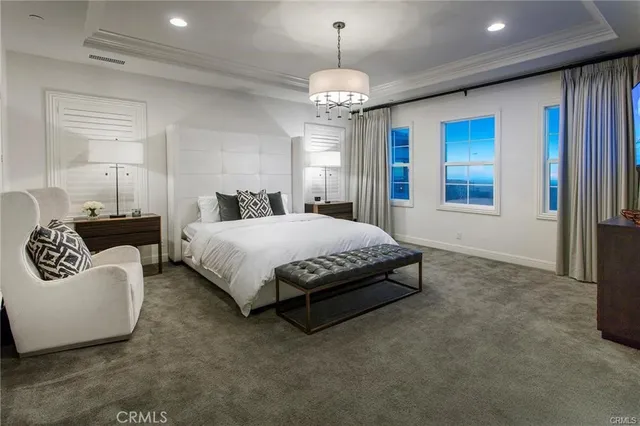 a spacious bedroom with a bed a couch and a chandelier