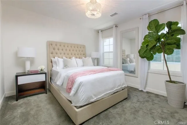 a bed sitting in a bedroom next to a window and a lamp