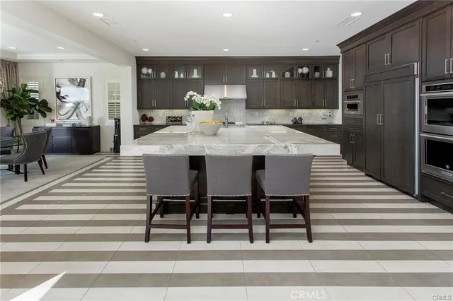 a kitchen with stainless steel appliances kitchen island granite countertop a table chairs sink and cabinets