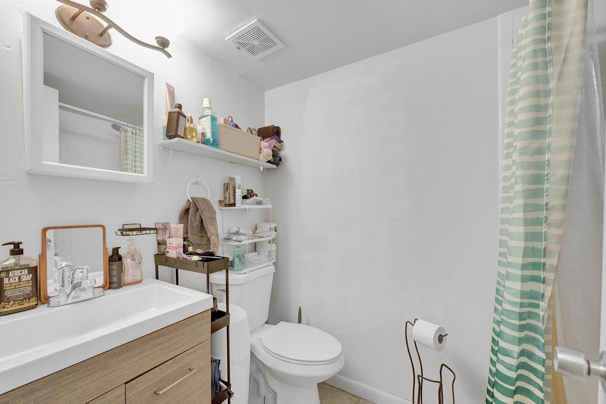 3396 Foxcroft Road, Unit 106 Miramar, FL 33025 - Photo 12 of 24 a bathroom with a sink a toilet and shower curtain