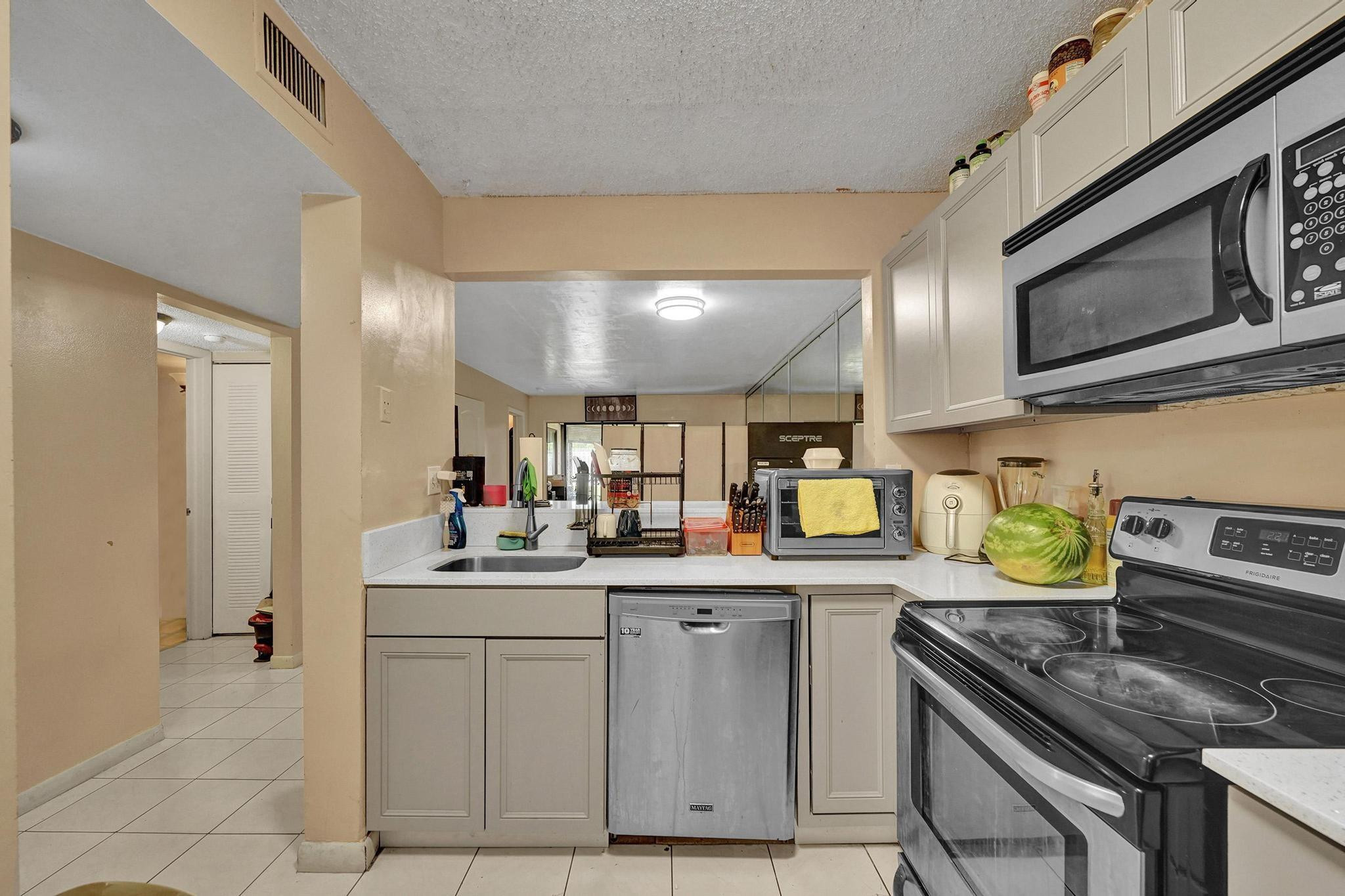 3396 Foxcroft Road, Unit 106 Miramar, FL 33025 - Photo 4 of 24 a kitchen with stainless steel appliances a stove a sink and a microwave