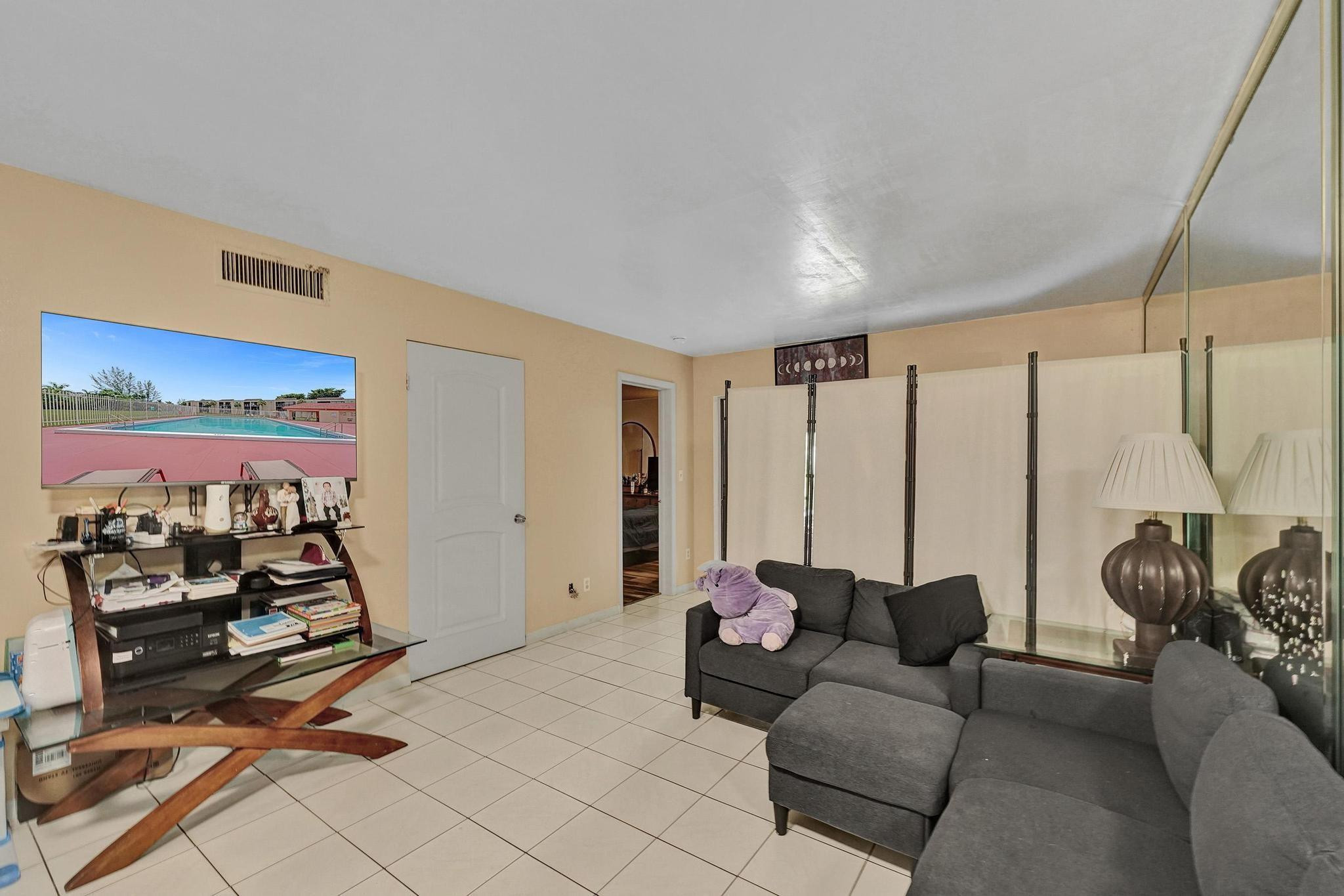 3396 Foxcroft Road, Unit 106 Miramar, FL 33025 - Photo 6 of 24 a living room with furniture a flat screen tv and a large window