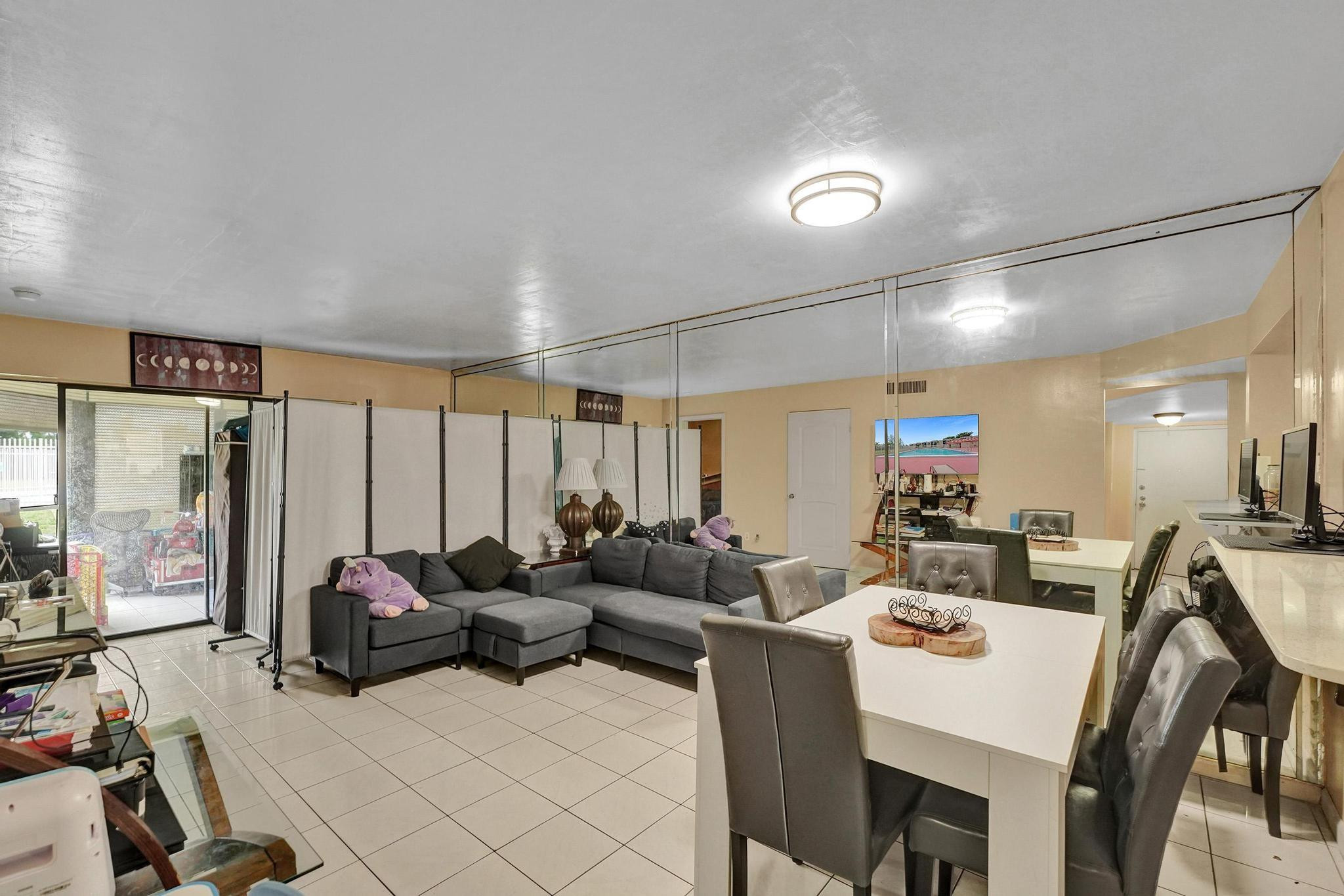 3396 Foxcroft Road, Unit 106 Miramar, FL 33025 - Photo 8 of 24 a living room with furniture a flat screen tv and a large window