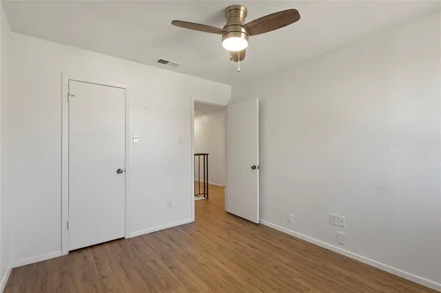 an empty room with wooden floor closet and ceiling fan