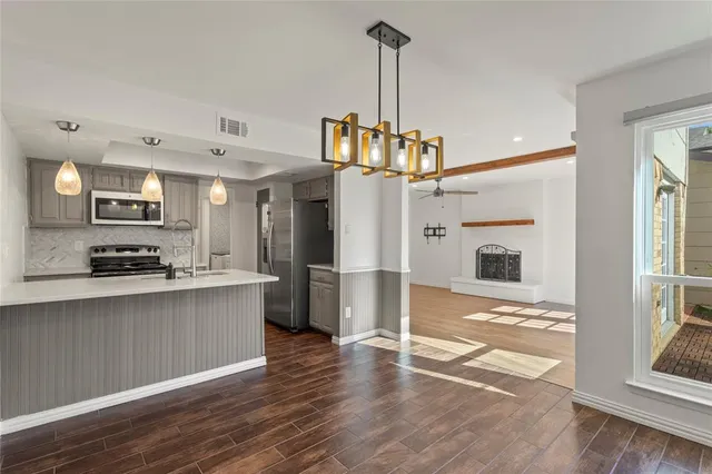 a view of a kitchen with kitchen island a counter space a sink appliances and cabinets