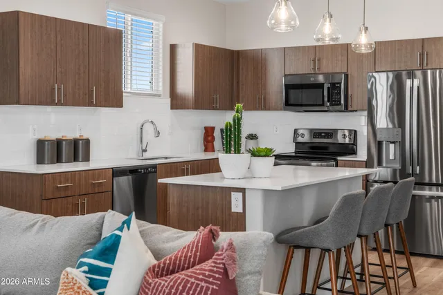 a kitchen with a refrigerator a microwave a sink and chairs