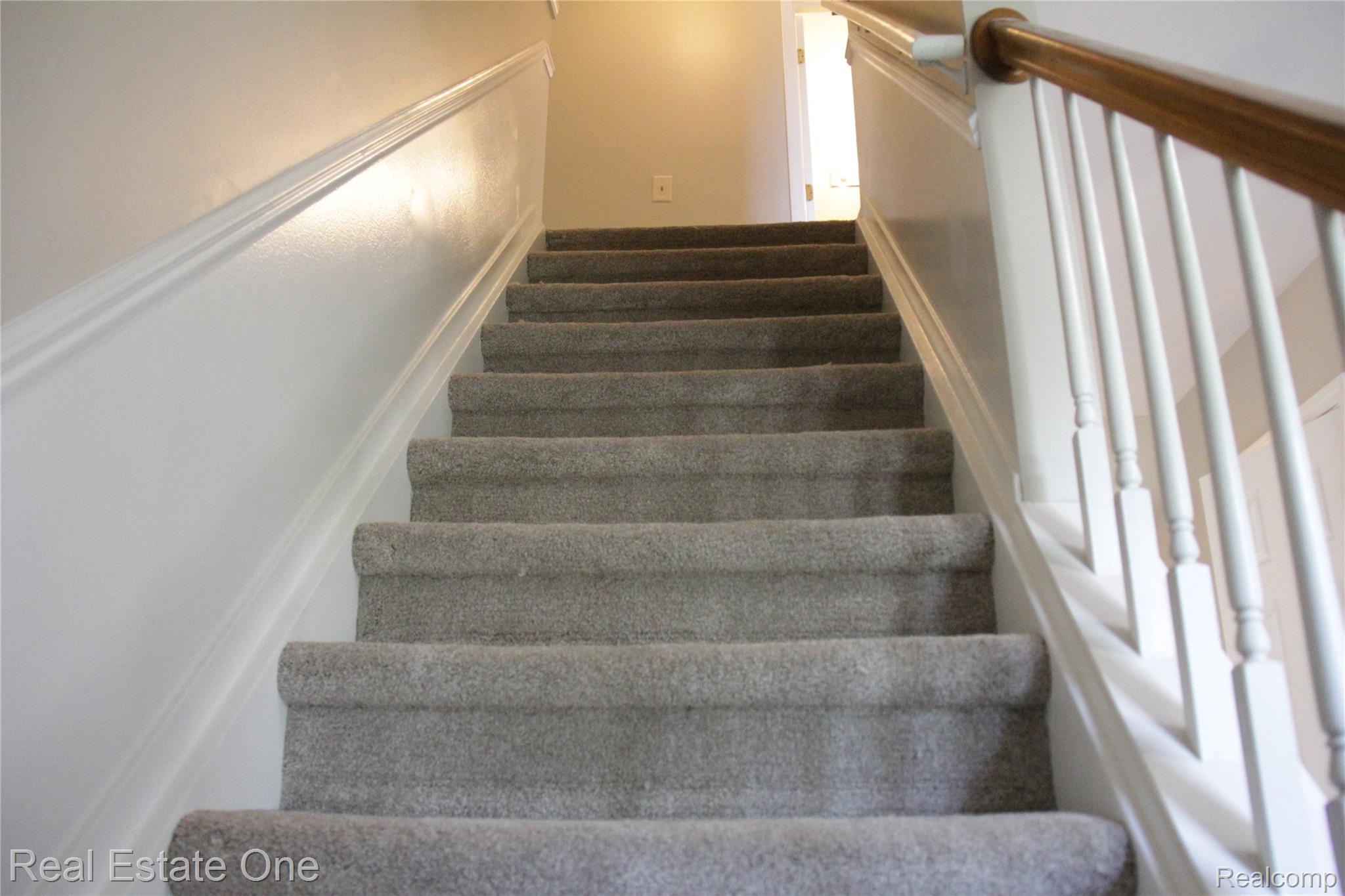 44777 Saltz Road Canton, MI 48187 - Photo 32 of 65 Carpeted staircase with white balusters and a wood handrail