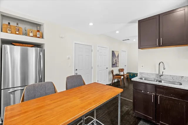 a kitchen with stainless steel appliances kitchen island a table chairs in it and wooden floors