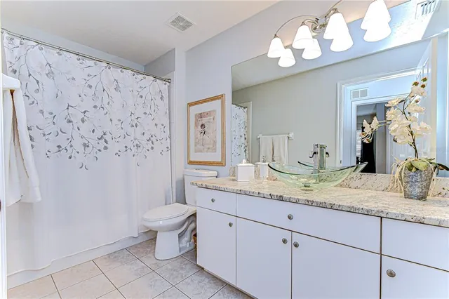 a bathroom with a granite countertop sink a toilet and a large mirror