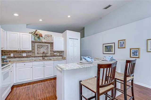 a kitchen with granite countertop white cabinets and chairs